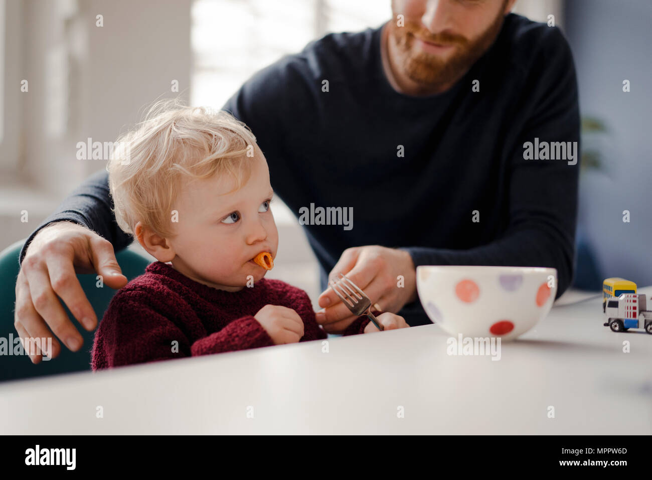 Padre alimentando il suo piccolo figlio con pasta Foto Stock