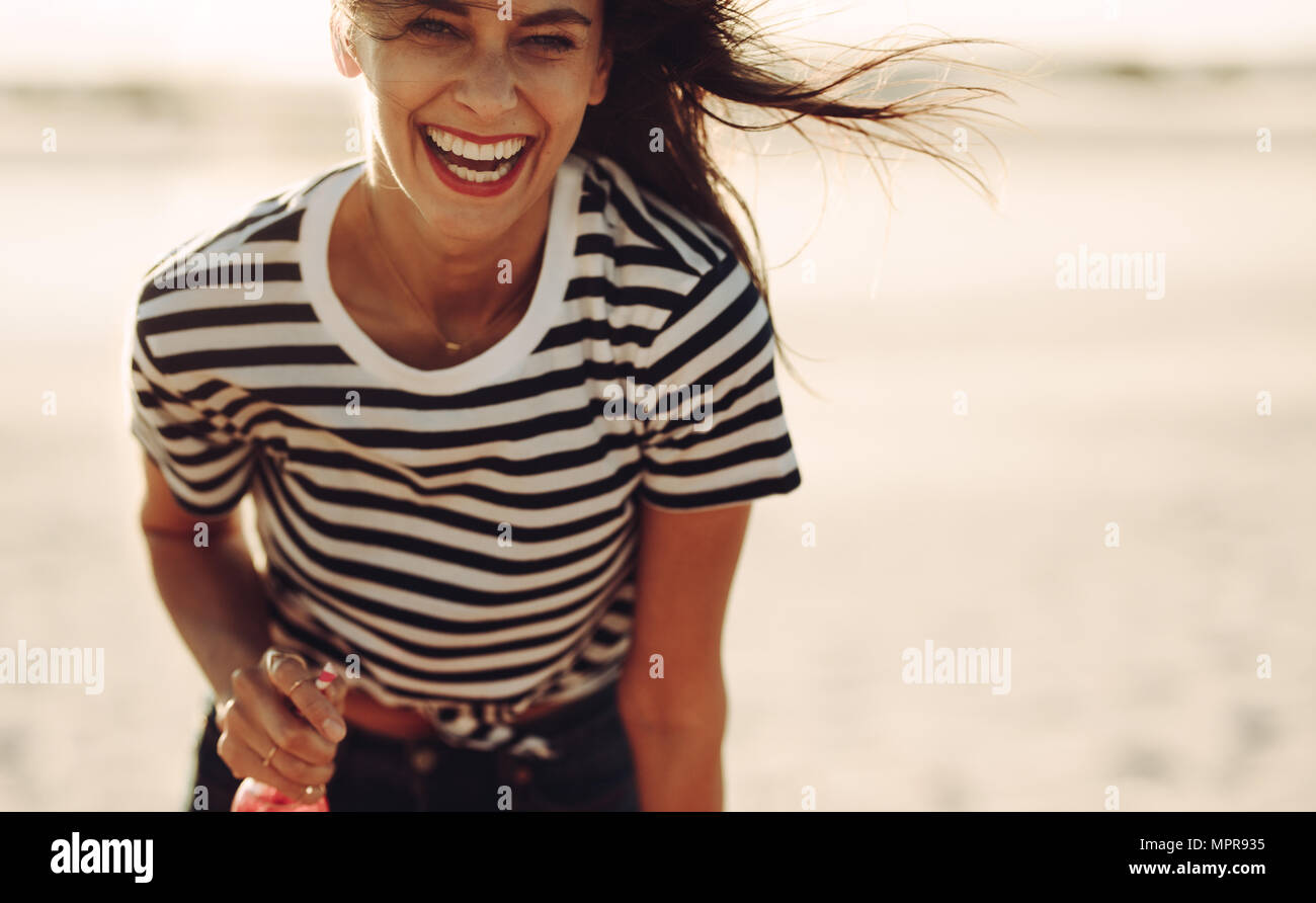Sorridente giovane donna in piedi in esterni con una bibita in mano. Donna godendo all'aperto su un giorno d'estate. Foto Stock