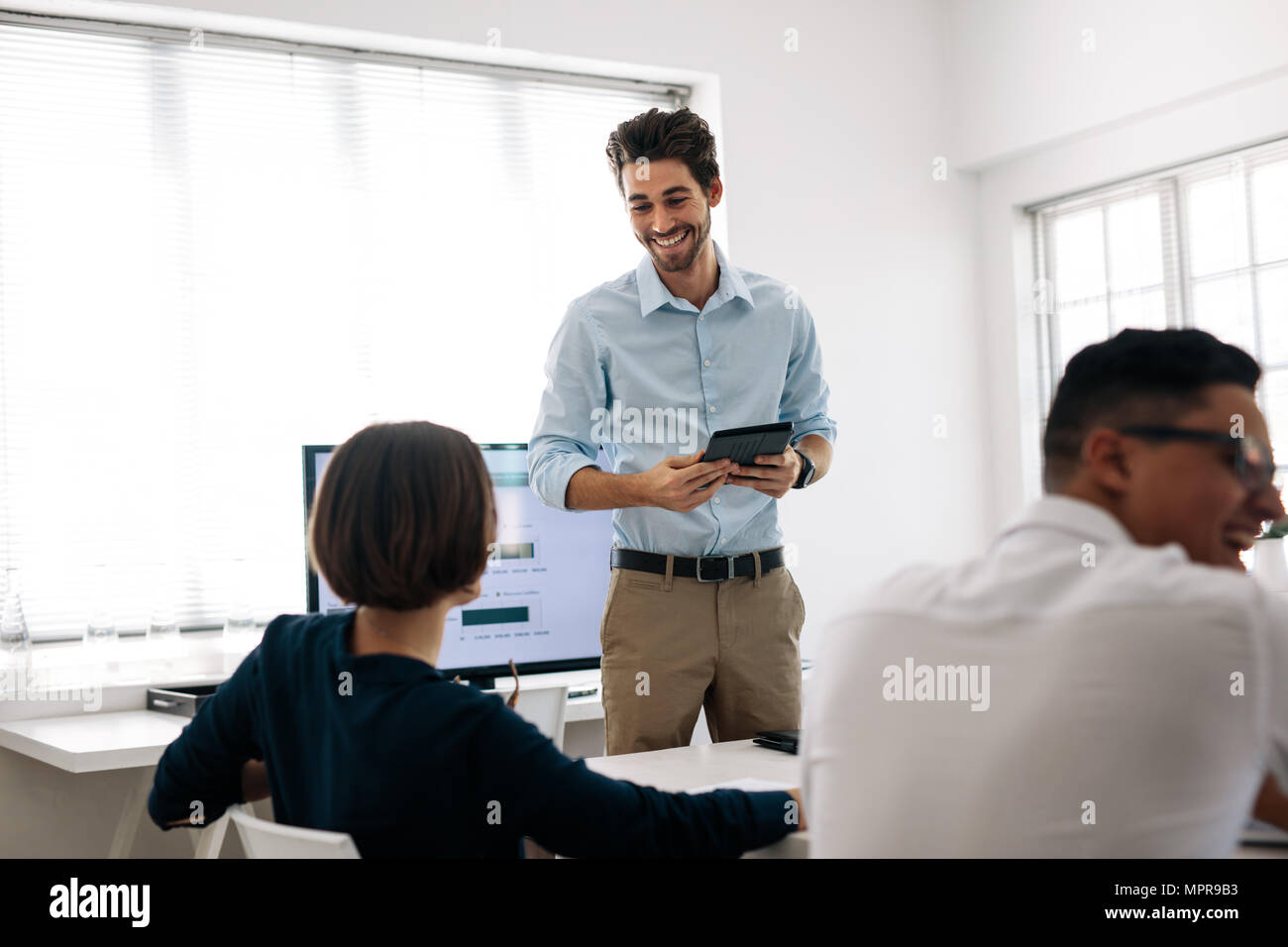Imprenditore fare una presentazione ai suoi colleghi in ufficio. Ufficio i colleghi la condivisione dei momenti più leggera seduta presso la sala conferenze. Foto Stock