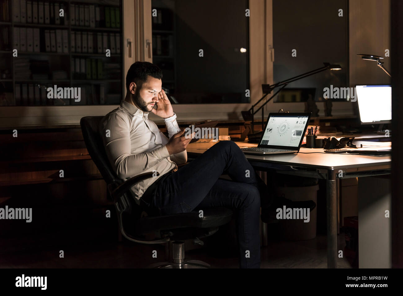 Imprenditore utilizzando tablet in ufficio di notte Foto Stock