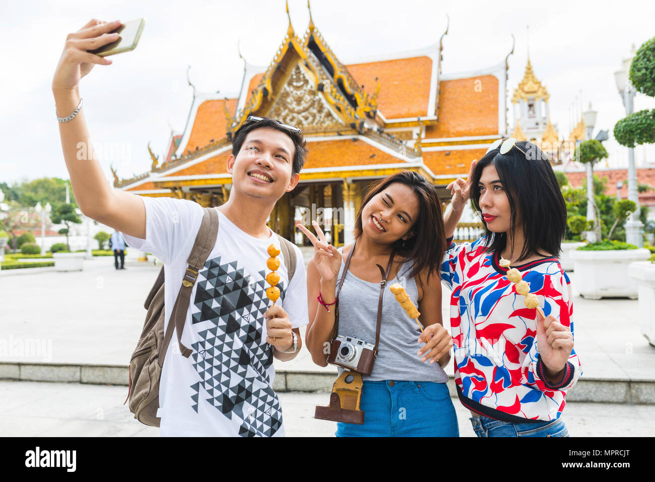 Thailandia, Bangkok, tre amici con cibo di strada prendendo selfie Foto Stock