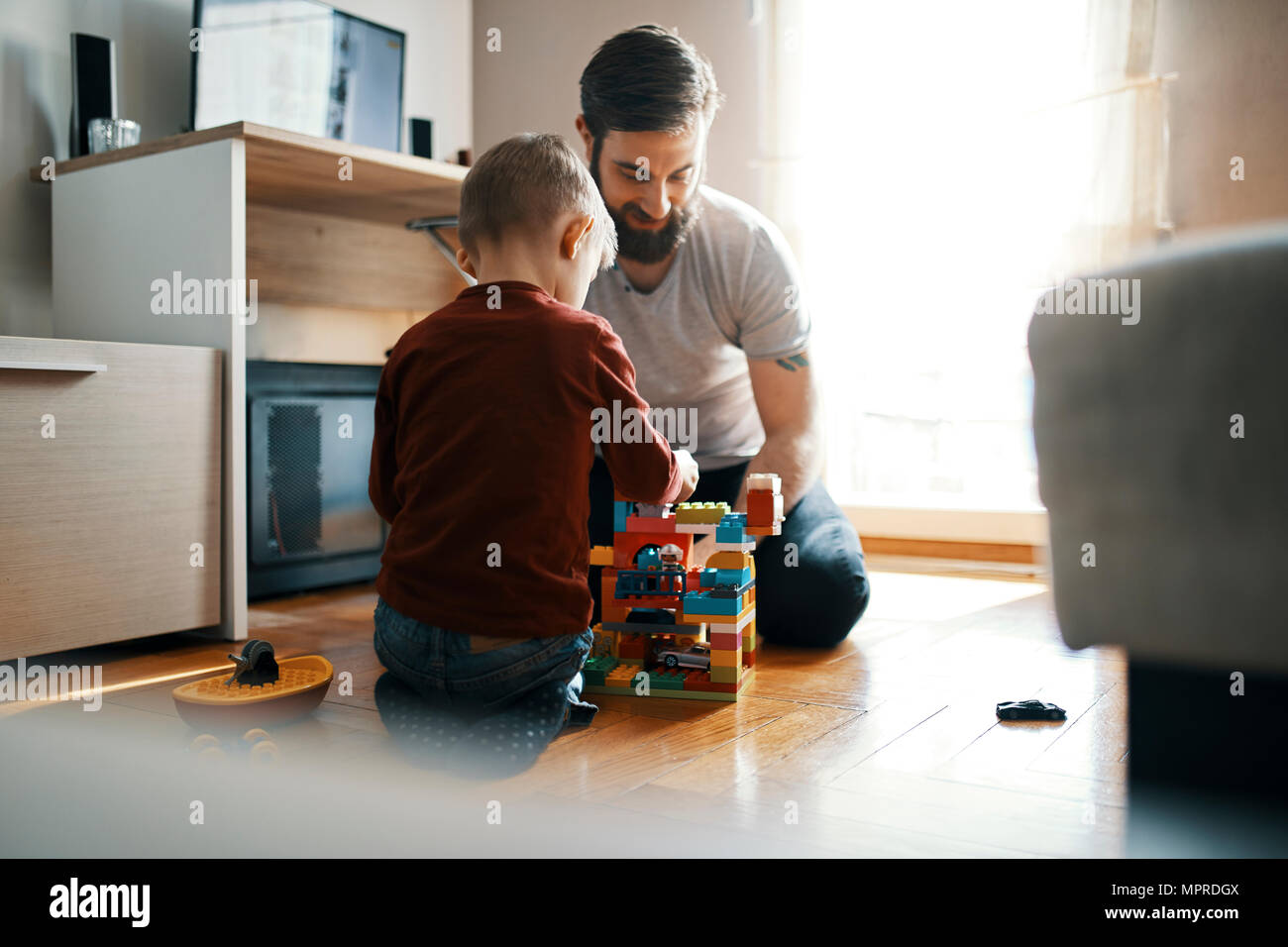 Padre e Figlio seduto sul pavimento a casa insieme giocando con mattoni da costruzione Foto Stock