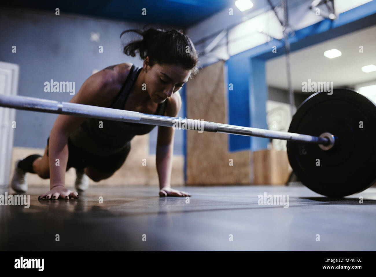 Donna facendo spingere ups a barbell in palestra Foto Stock