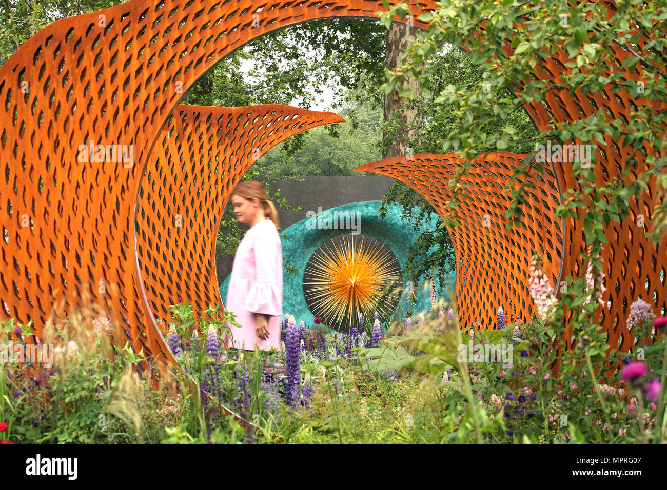 Una donna cammina passato il David Harbor e Savills giardino, durante la RHS Chelsea Flower Show presso il Royal Hospital Chelsea, Londra. Foto Stock