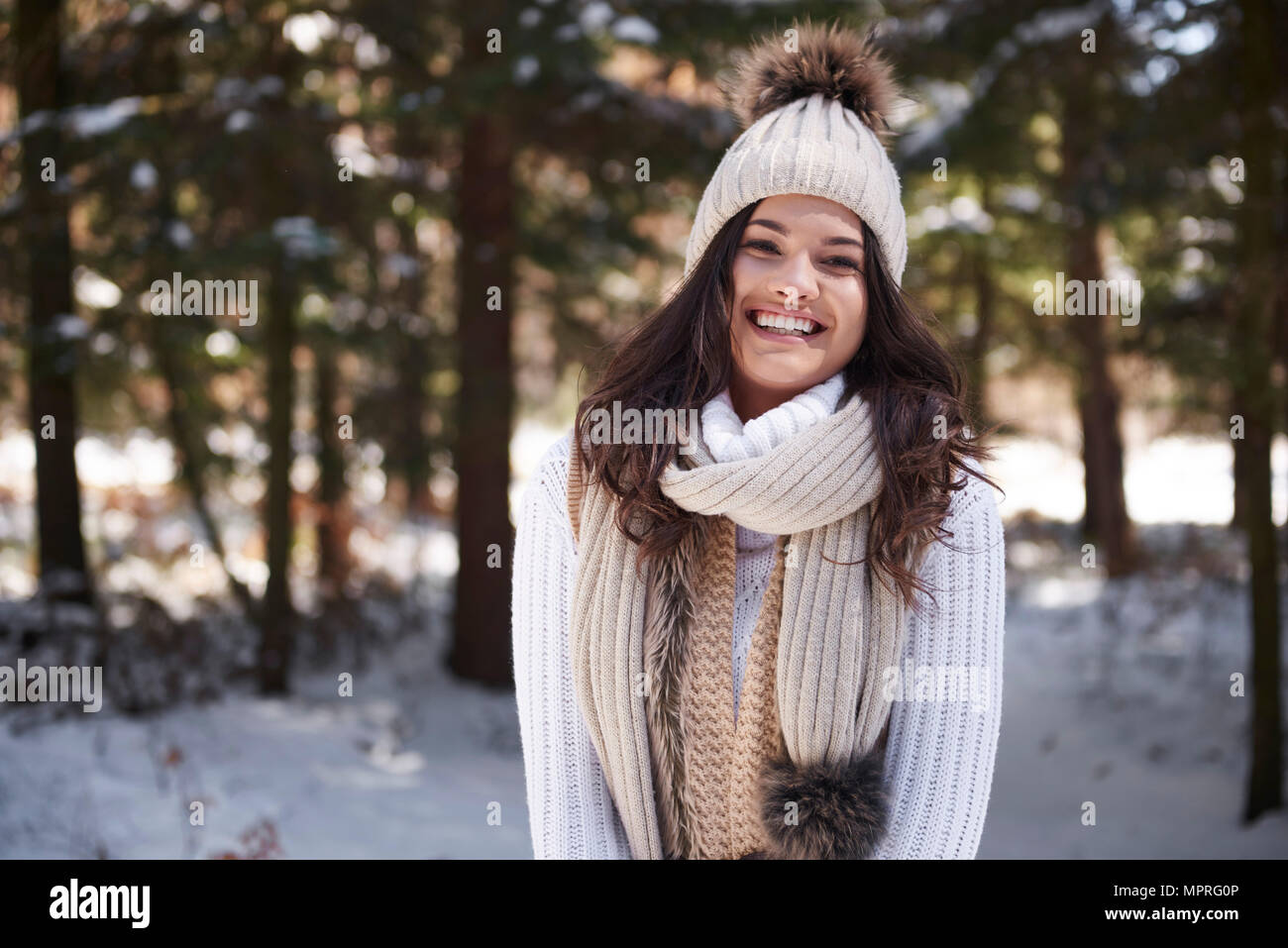 Ritratto di ridere giovane donna che indossa la maglieria nella foresta di inverno Foto Stock