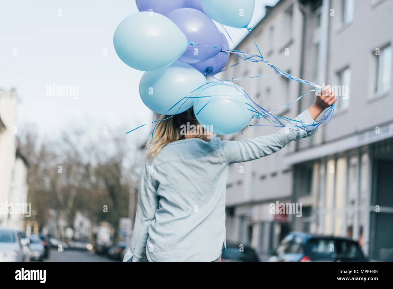 Vista posteriore della donna con palloncini blu Foto Stock