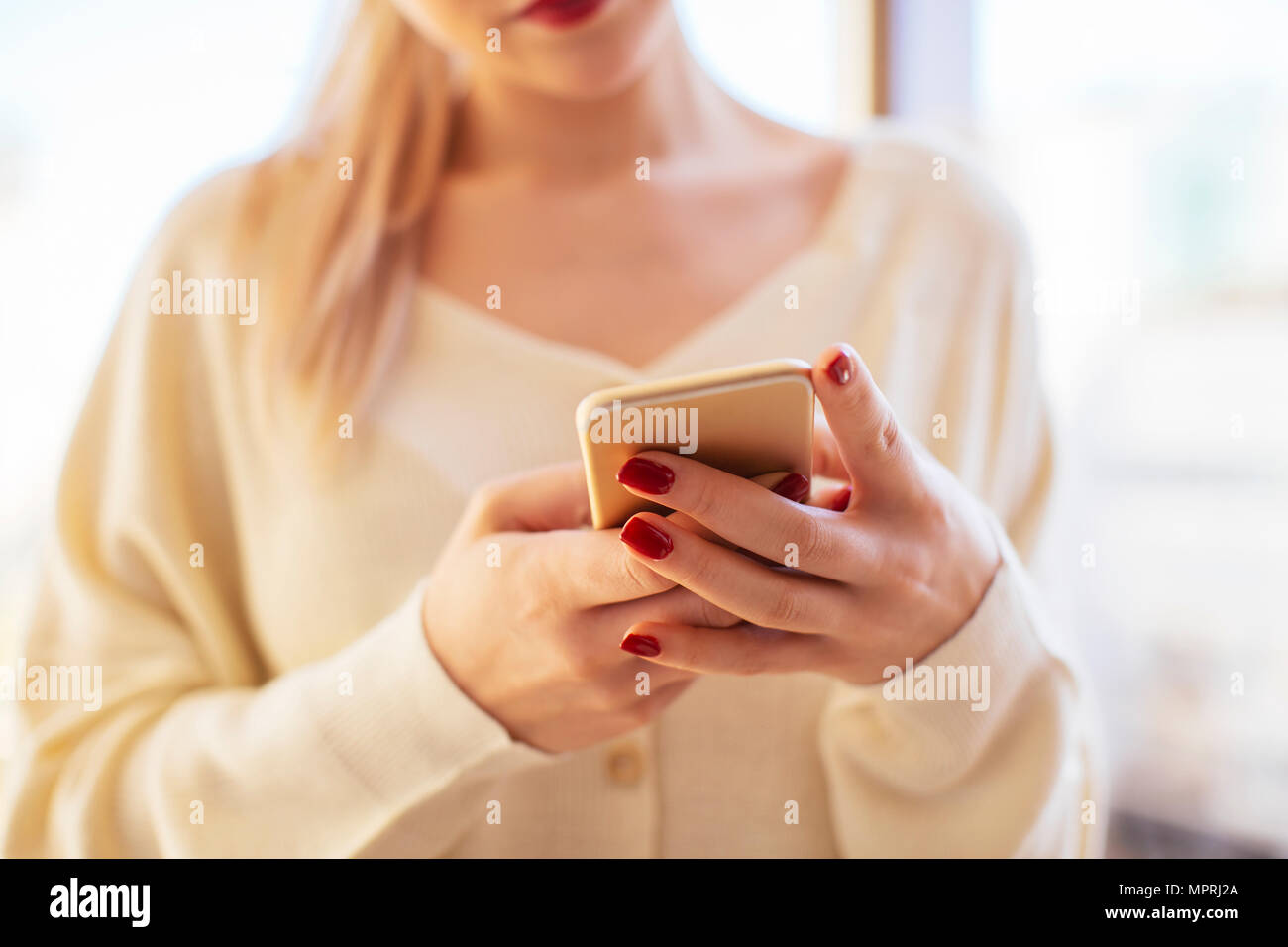 Donna bionda utilizza lo smartphone a casa Foto Stock
