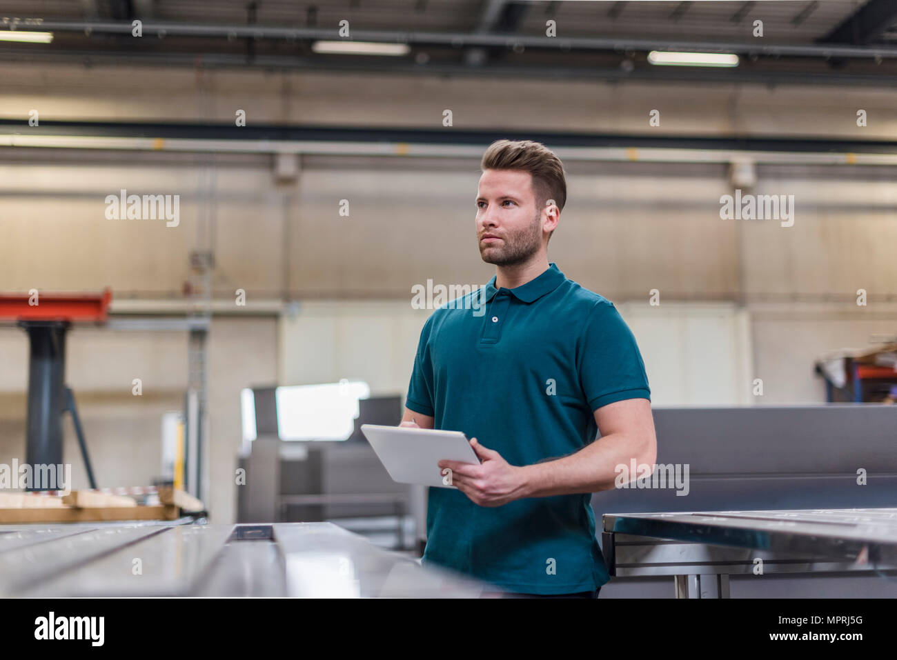 L'uomo con la compressa sulla fabbrica negozio guardando intorno Foto Stock