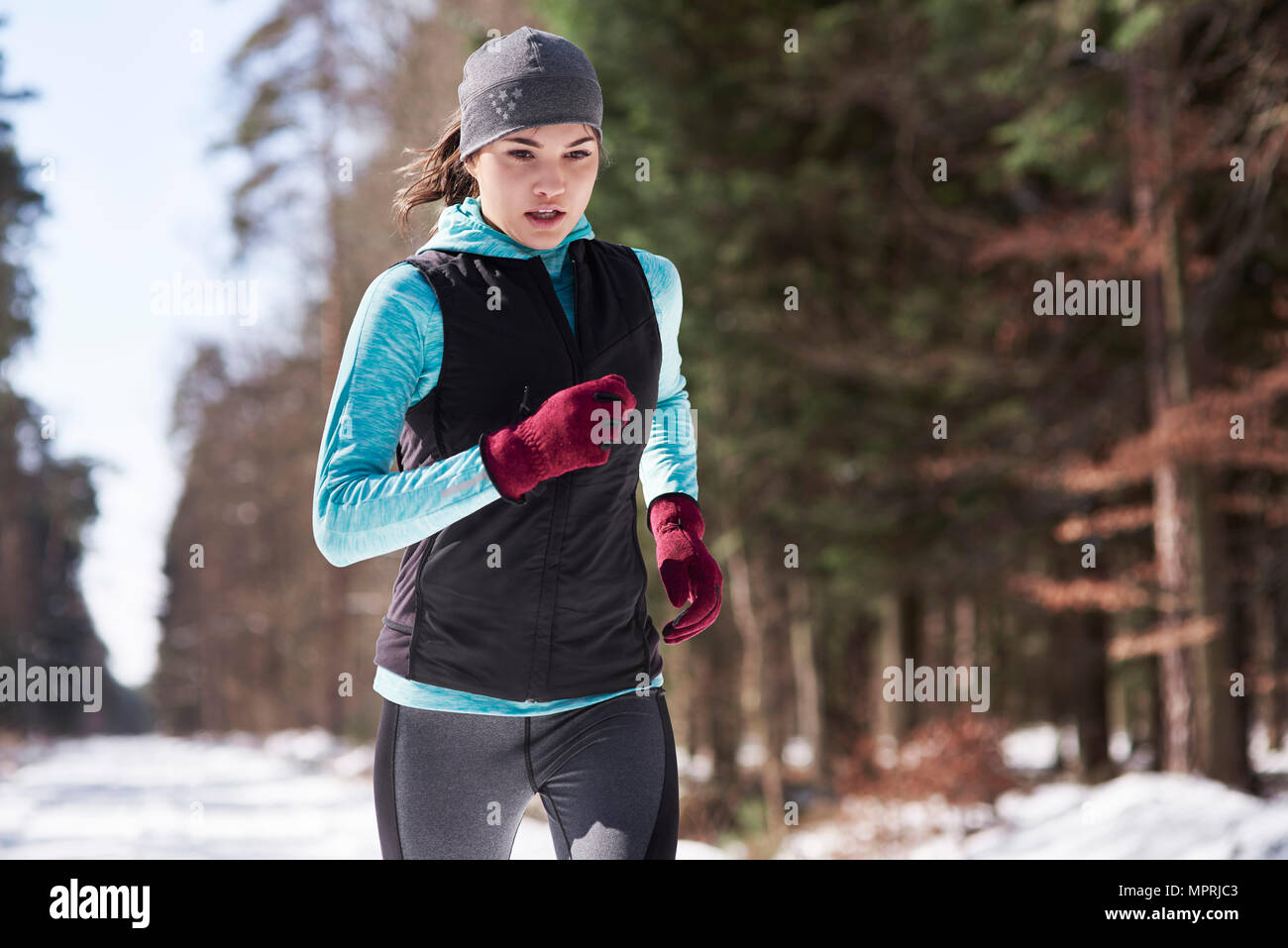 Giovane donna fare jogging nel bosco invernale Foto Stock
