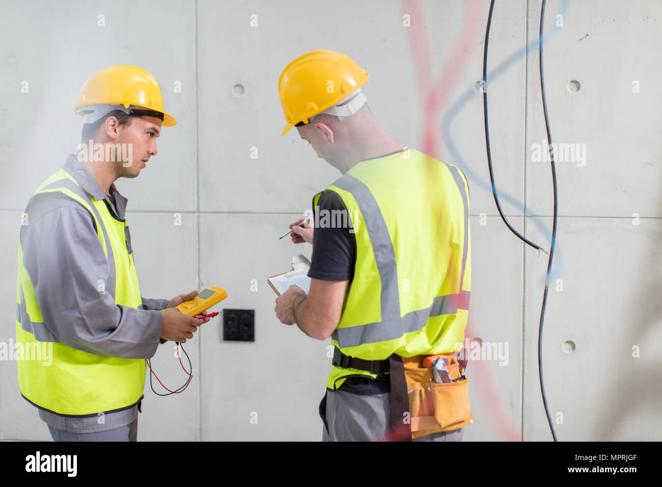 Elettricisti lavorando sul sito in costruzione Foto Stock