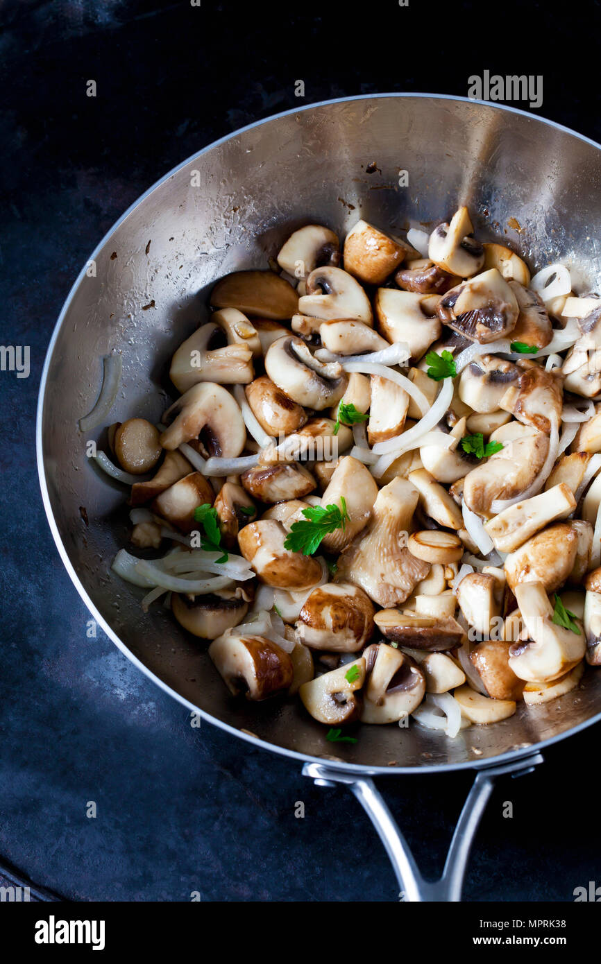 Champignon fritti e re tromba funghi con cipolle e prezzemolo in padella Foto Stock