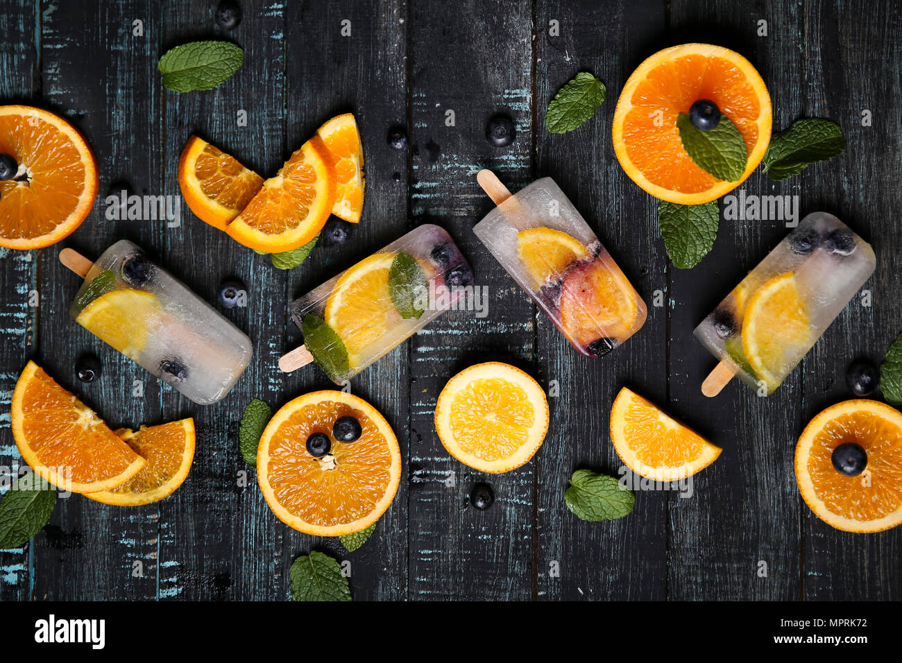 In casa detox popsicles con mirtilli, fettine di arancia e foglie di menta sul legno nero Foto Stock