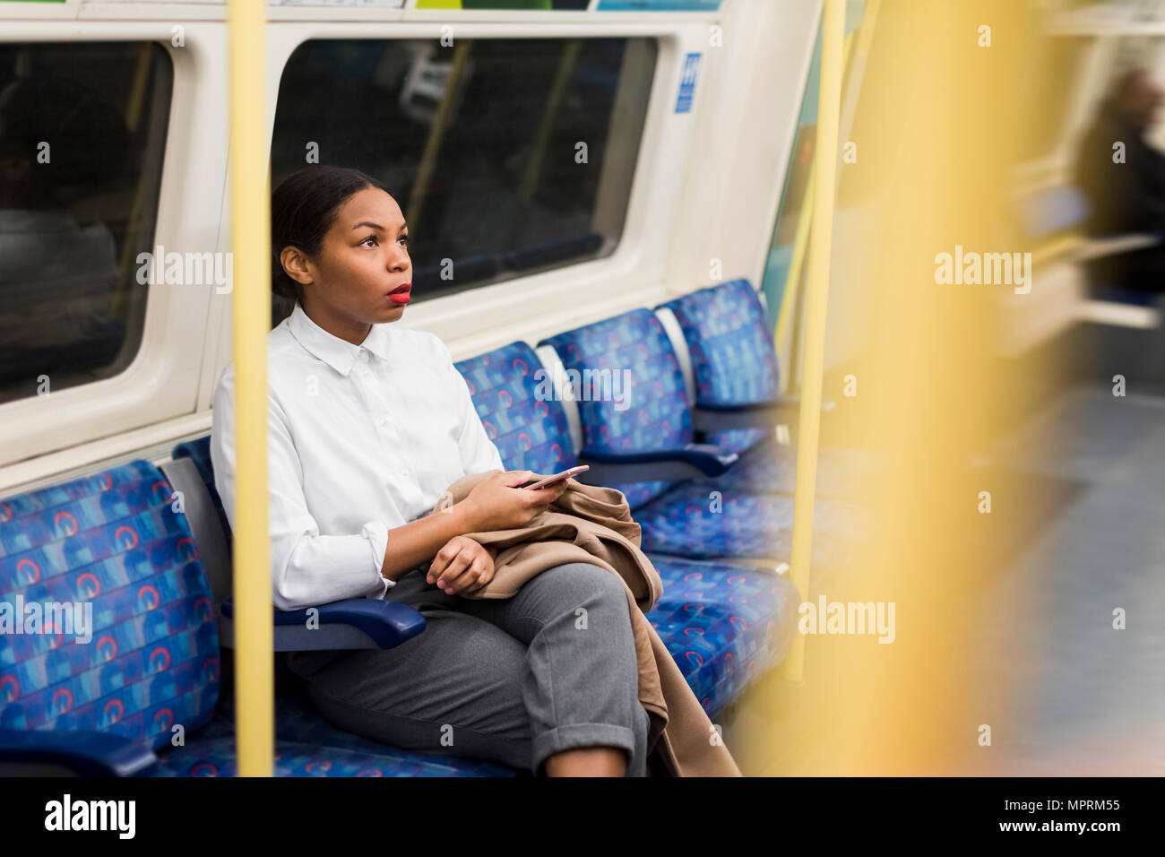 UK, Londra, imprenditrice con un telefono cellulare seduti in treno sotterraneo Foto Stock