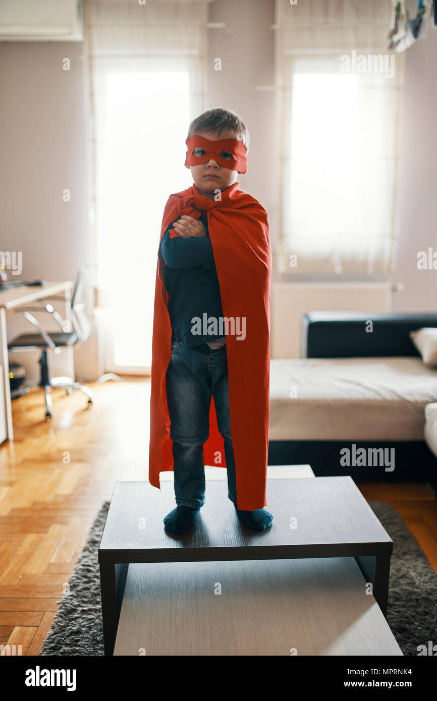 Little Boy vestito come un supereroe in piedi sul tavolo da caffè a casa  Foto stock - Alamy