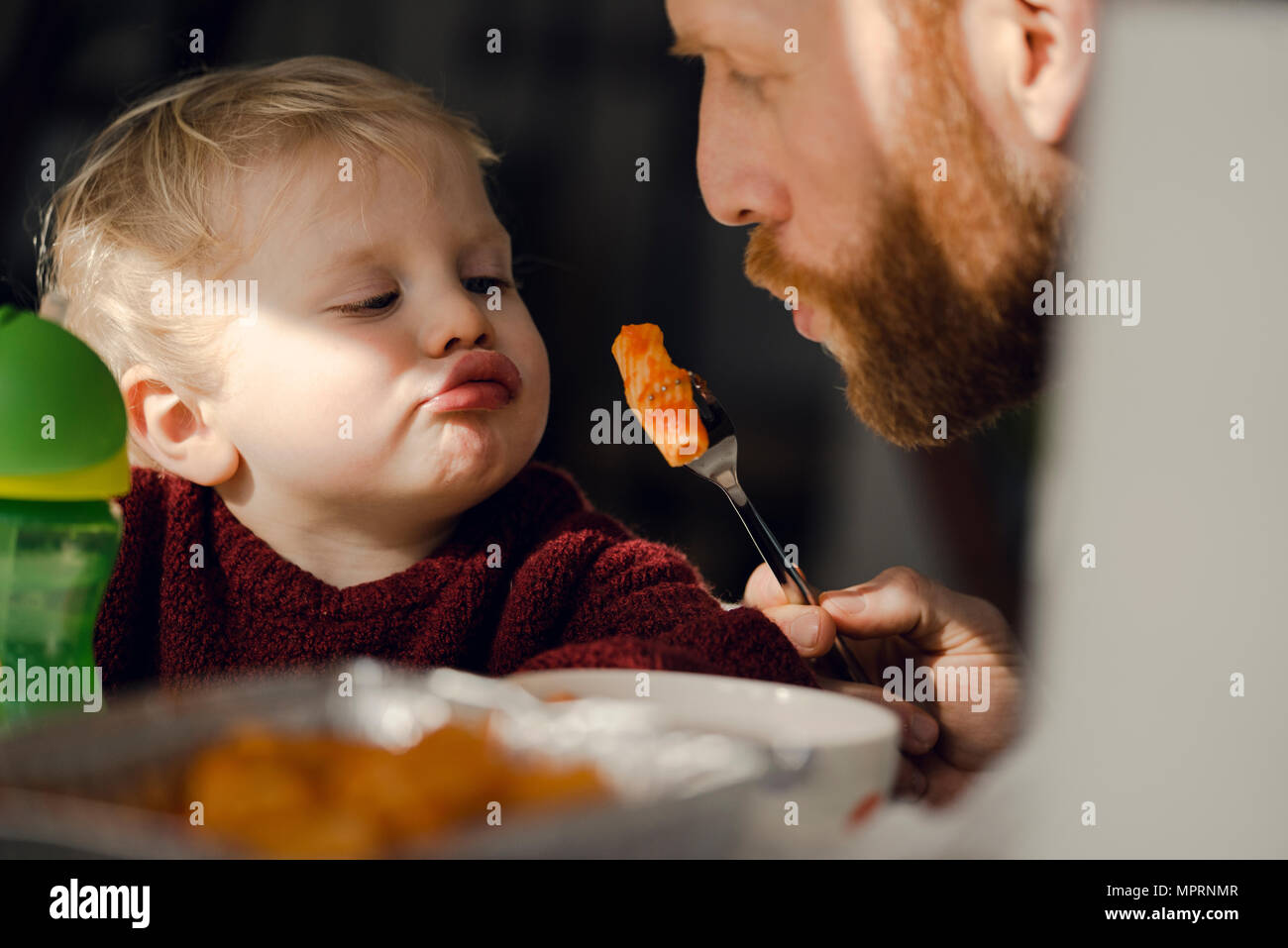 Padre alimentando il suo piccolo figlio con gustosi piatti di pasta Foto Stock