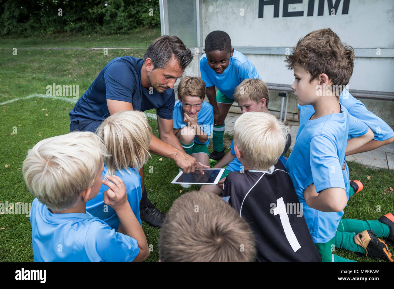Pullman con tablet e giovani calciatori sul terreno di calcio Foto Stock