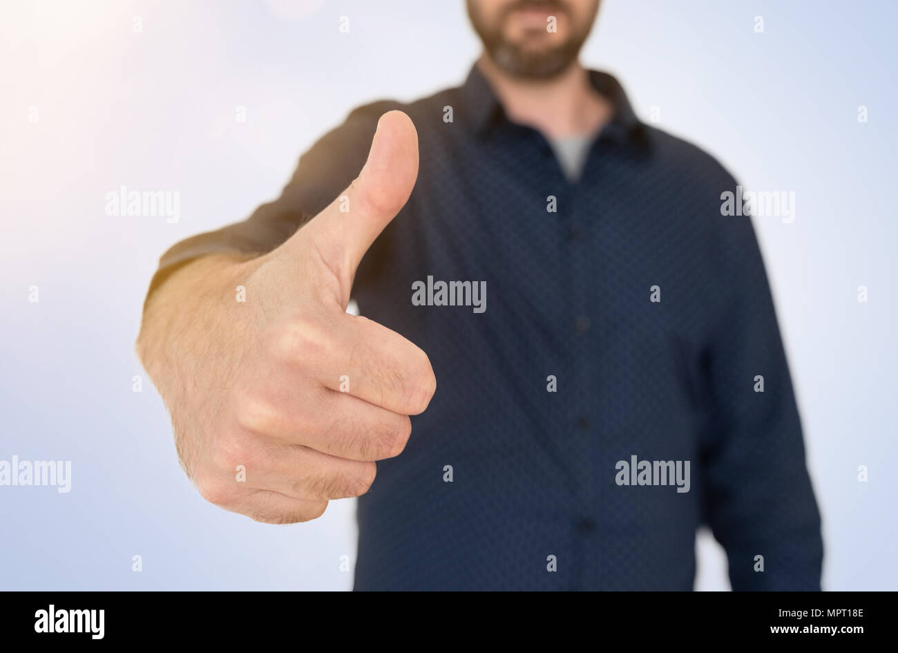 Imprenditore in maglietta blu che mostra Thumbs up gesto Foto Stock