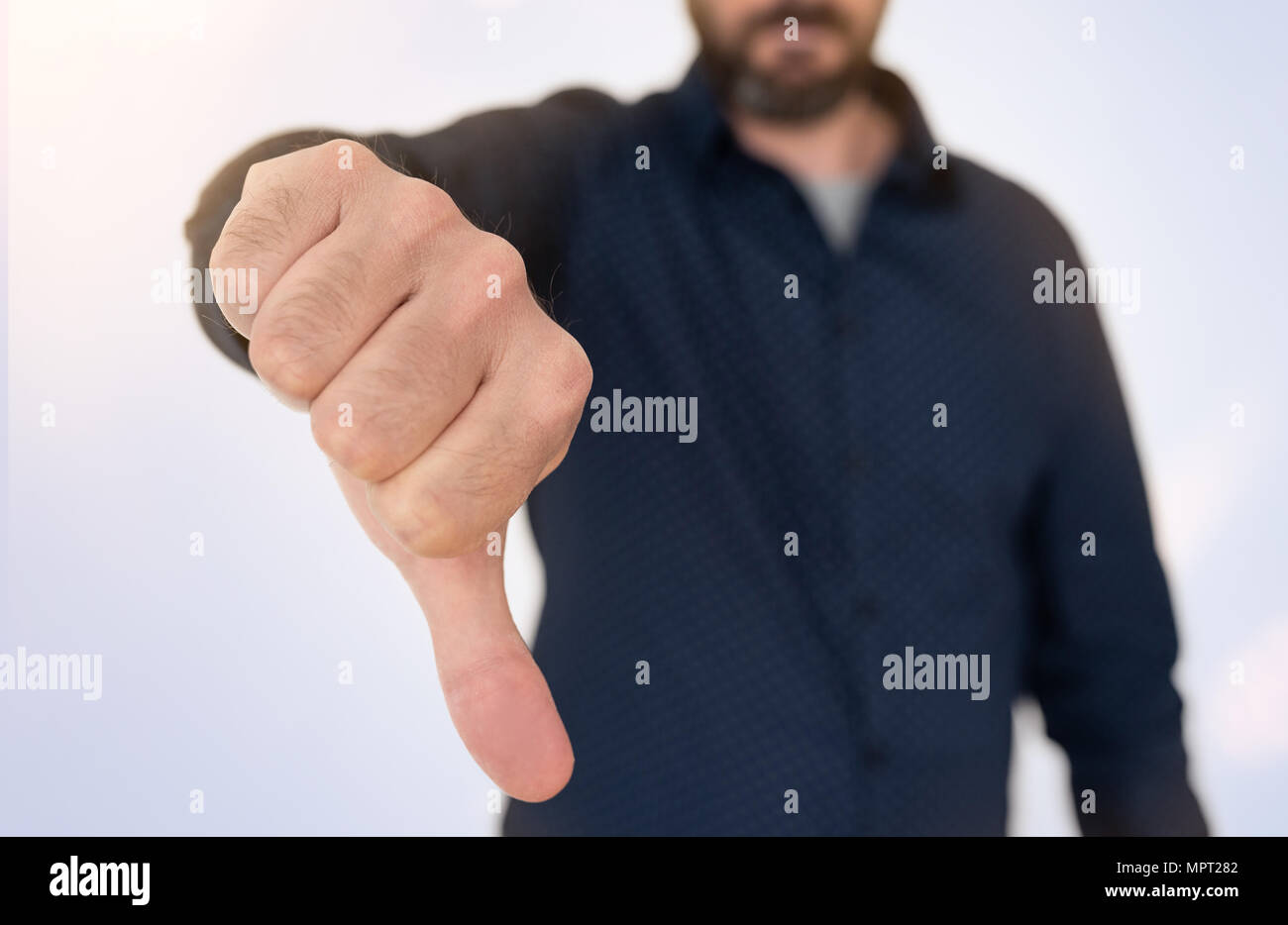 Imprenditore in maglietta blu che mostra il pollice verso il basso gesto Foto Stock