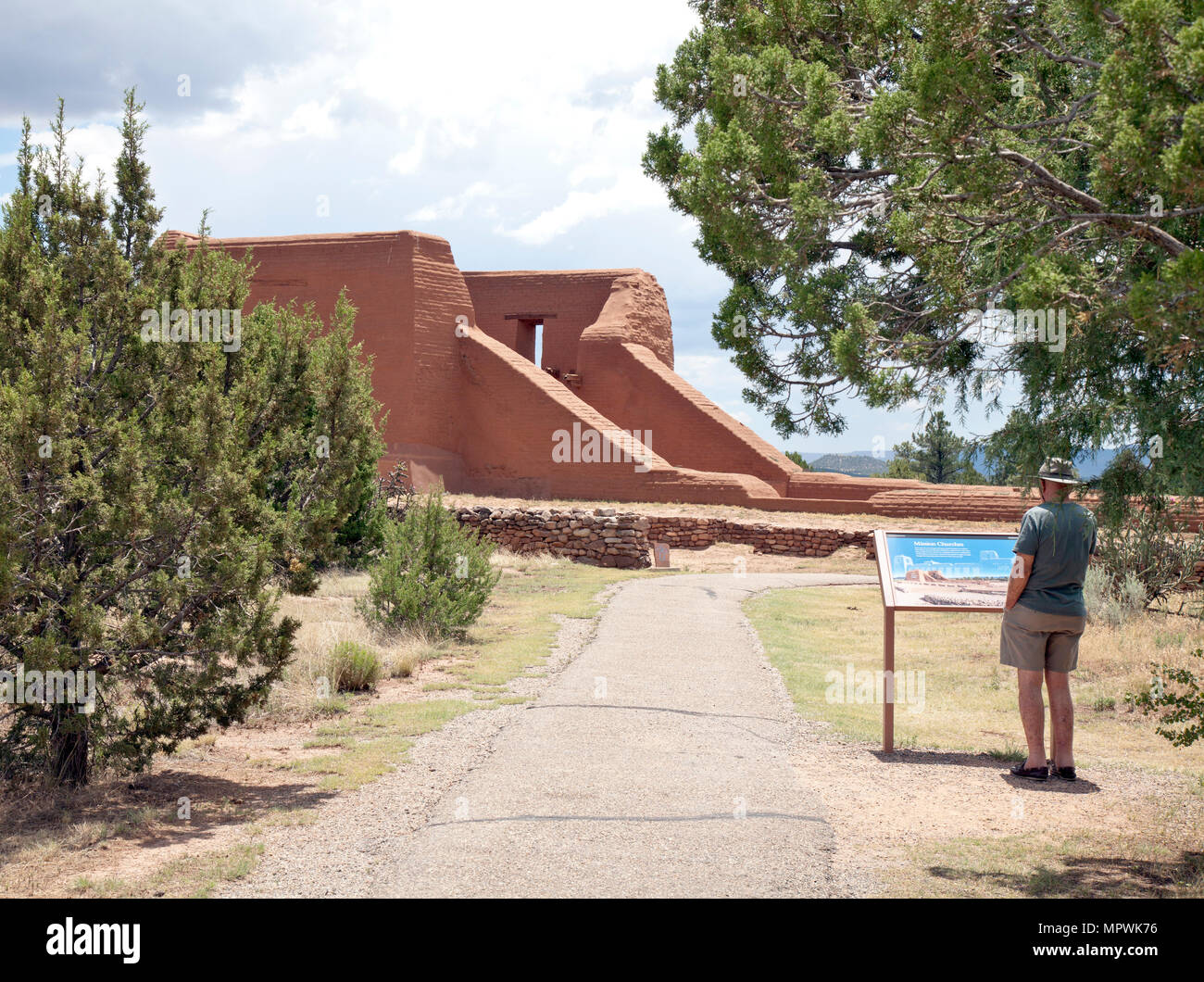 Un visitatore studi information board prima di esplorare le rovine di un palazzo del diciottesimo secolo missione francescana chiesa a Pecos National Historical Park, Pec Foto Stock