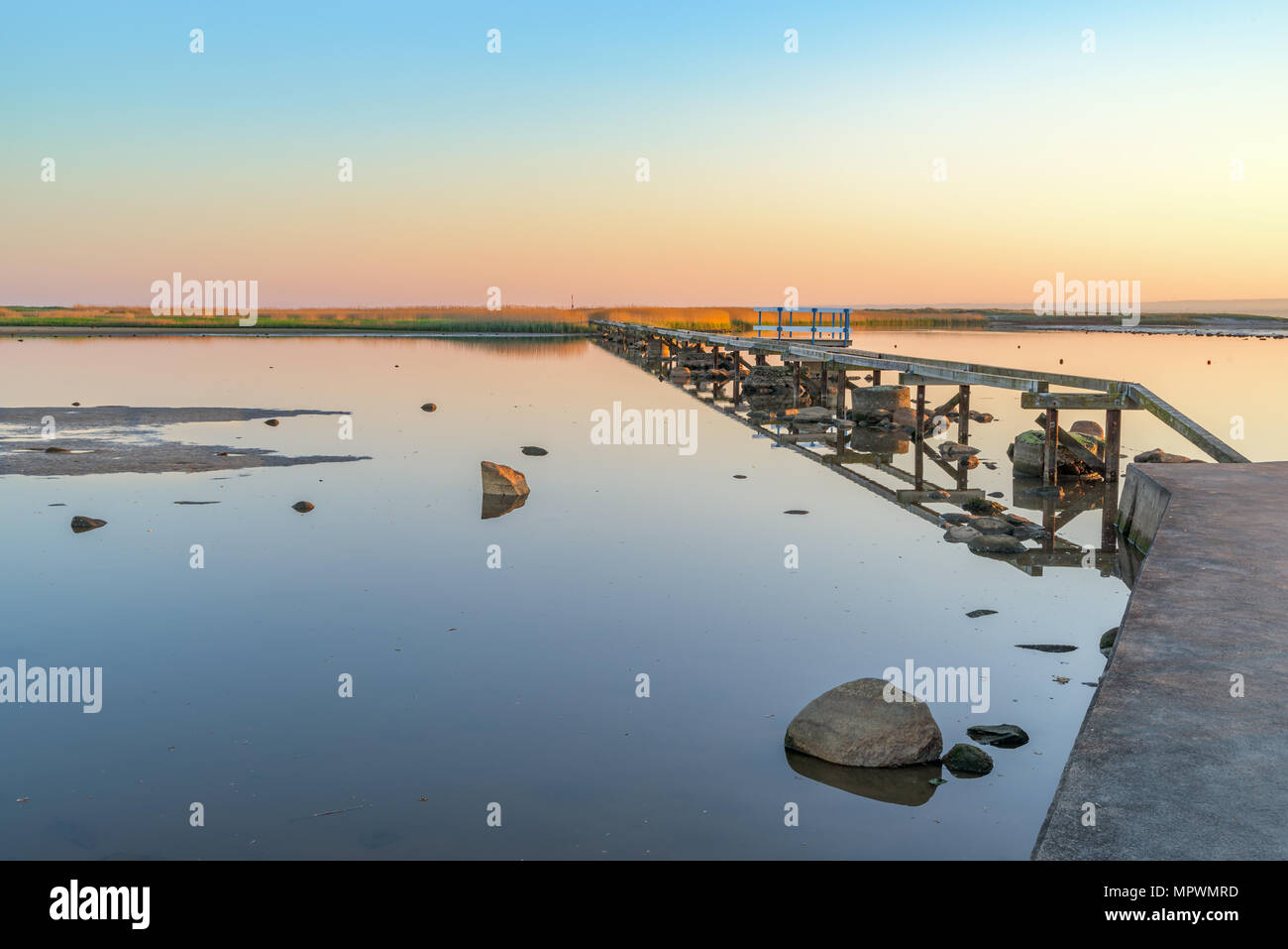 La fondazione di un molo in legno su un riflettenti mare su una bella mattina di primavera poco dopo l'alba. Ubicazione Utvalinge nella Svezia meridionale. Foto Stock