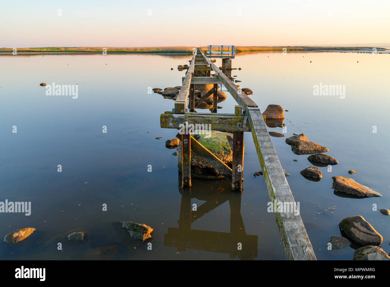 La fondazione di un molo in legno su un riflettenti mare su una bella mattina di primavera poco dopo l'alba. Ubicazione Utvalinge nella Svezia meridionale. Foto Stock