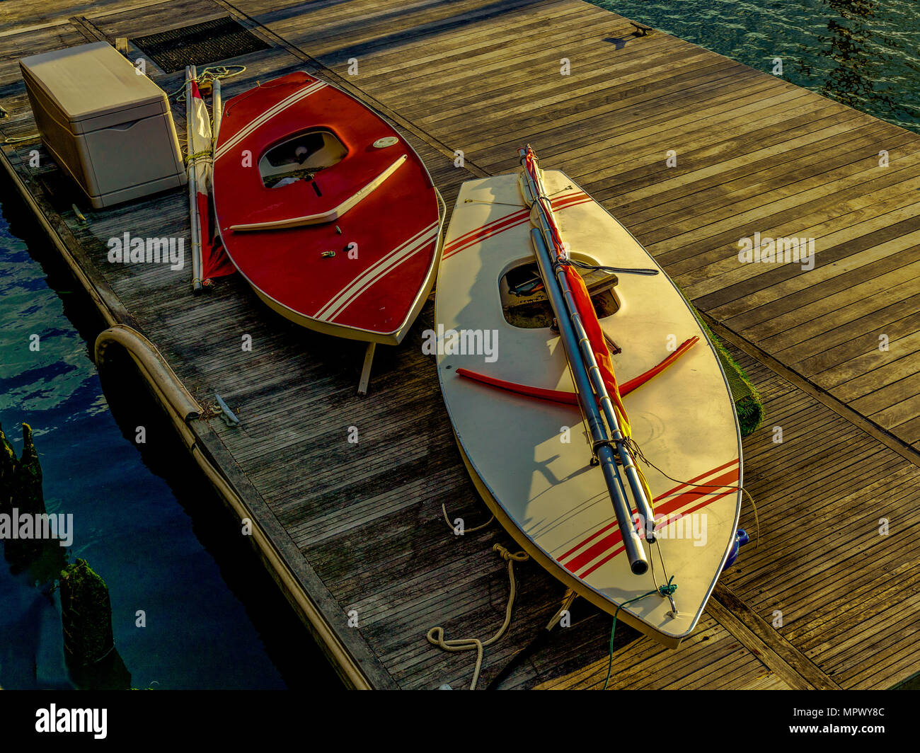 Due barche a vela personali sedersi sul dock a Liberty Marina di atterraggio in primavera. Alla fine del giorno luce dorata migliora la loro bellezza. Foto Stock