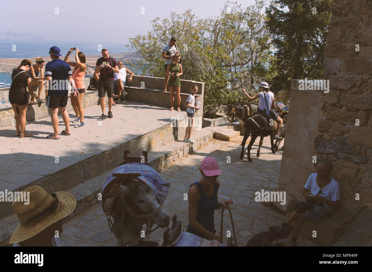 Lindos isola di Rodi, Grecia - 18 Settembre 2017: turisti relax e cavalcare gli asini a Lindos ai piedi dell'Acropoli. Foto Stock