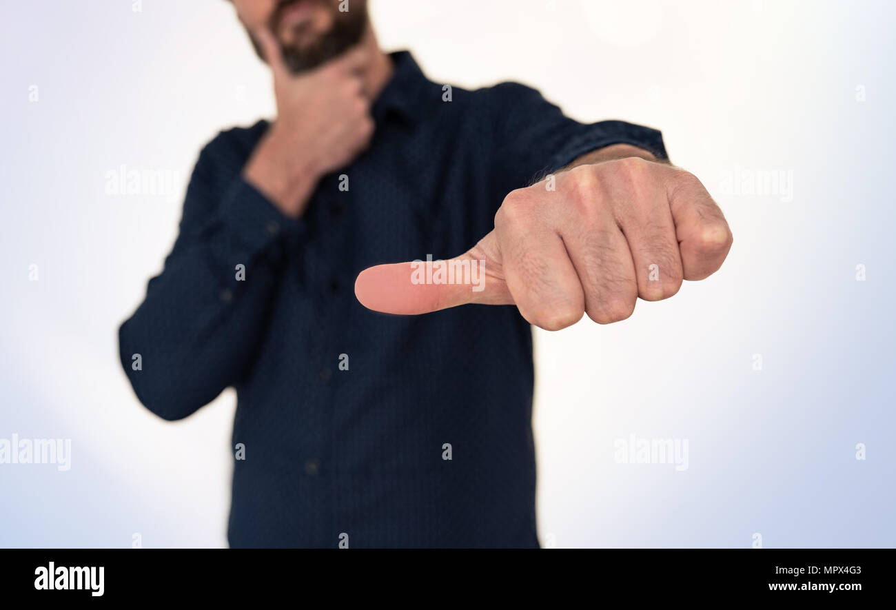 Uomo in camicia blu facendo mano gesto con il pollice lateralmente Foto Stock