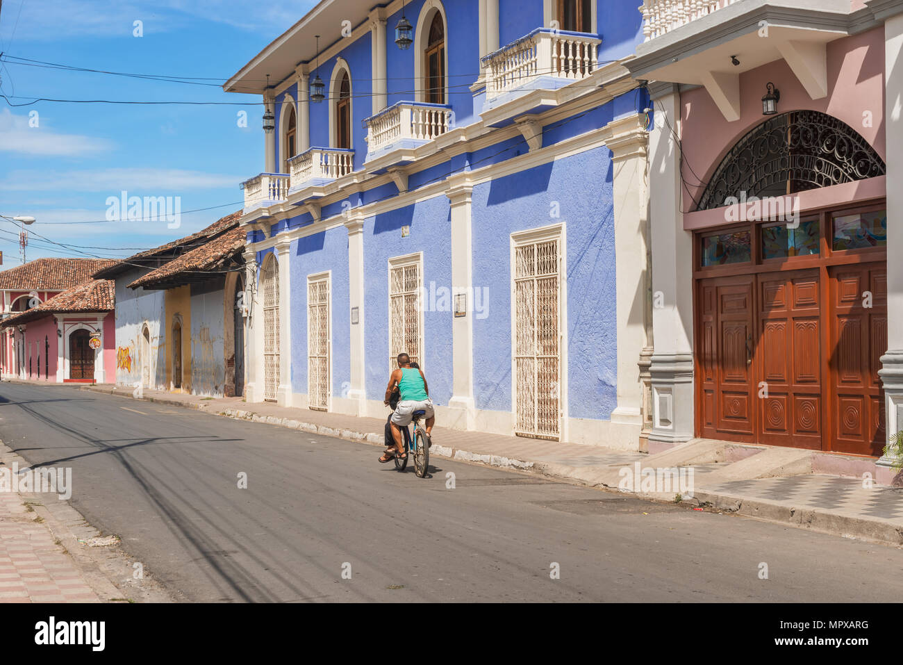Granada, Nicaragua - Novembre 20, 2016: l uomo è Bicicletta Equitazione sulla strada di colorate case commerciali nel quartiere storico di Granada in Nicar Foto Stock