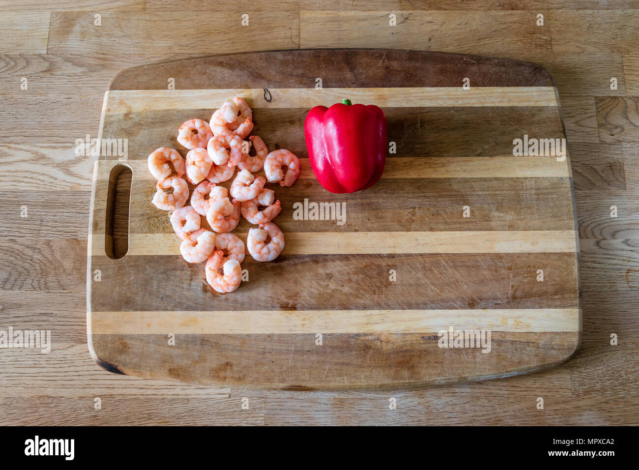 Materie e gamberetti e pepe su un tagliere Foto Stock