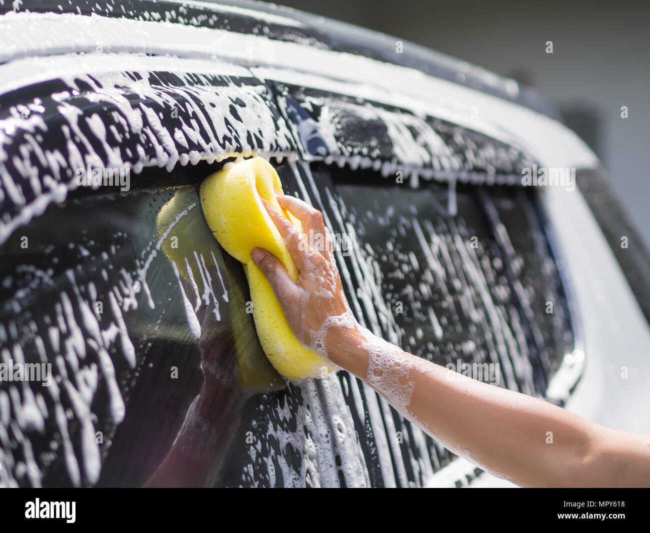 Donna con mano la spugna gialla il lavaggio auto Foto stock - Alamy