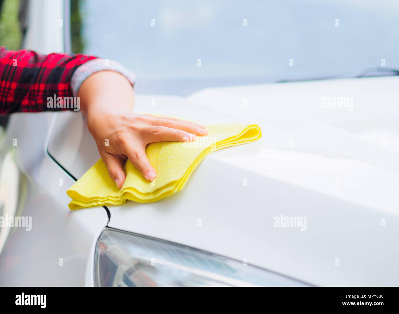 Mano con giallo panno in microfibra per la pulizia auto bianco. Foto Stock