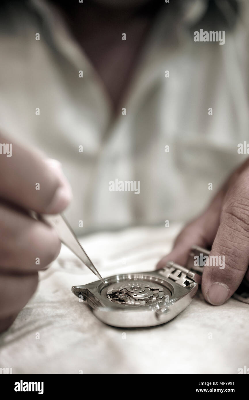 Sezione mediana dell uomo che ripara guarda sulla tabella in officina Foto Stock