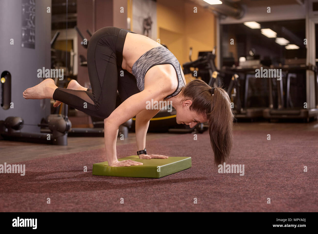 Per tutta la lunghezza della piegatura della donna durante la pratica handstand in palestra Foto Stock