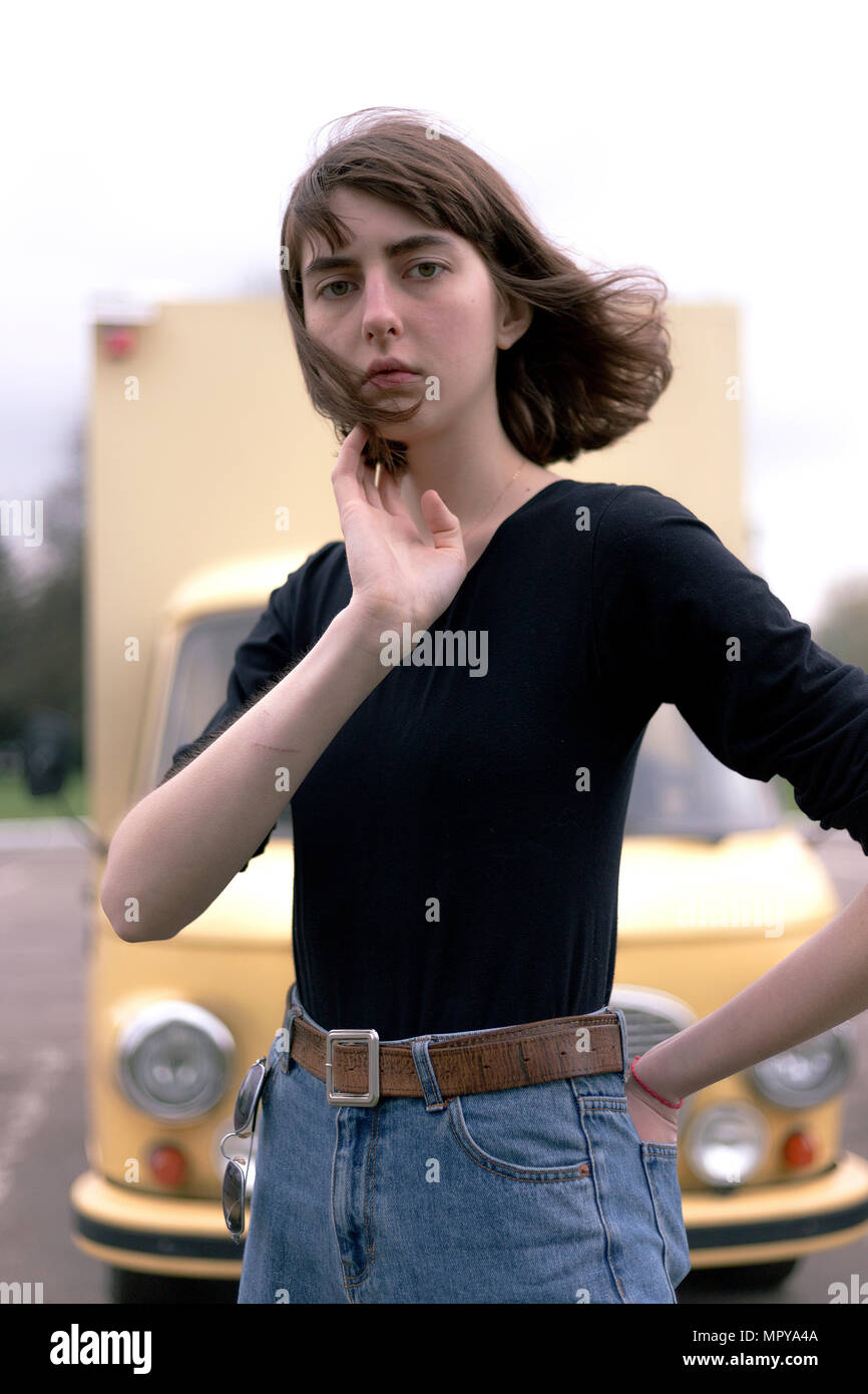 Ritratto di fiducioso giovane donna con la mano in tasca posteriore in piedi contro il carrello Foto Stock