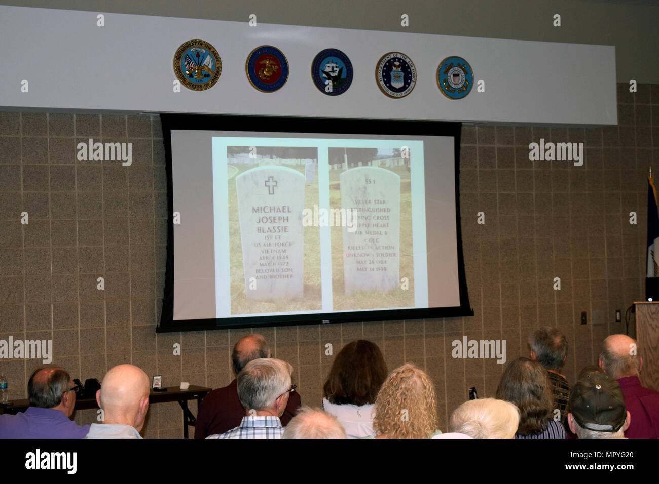 Lunedì notte Tom Tudor racconta la storia di Al Cimitero Nazionale di Arlington e la tomba del Milite Ignoto presso l'Iowa Stella d'Oro Museo Militare su Camp Dodge manovra comune centro di formazione in Johnston, Iowa. Come egli racconta la storia di 1Lt. Michael J. Blassic, inizialmente identificata come un ignoto, gli ospiti guardano al suo attuale headstone situato nel Jefferson Barracks a St. Louis, Missouri. (U.S. Air National Guard foto di Tech. Sgt. Michael McGhee/rilasciato) Foto Stock