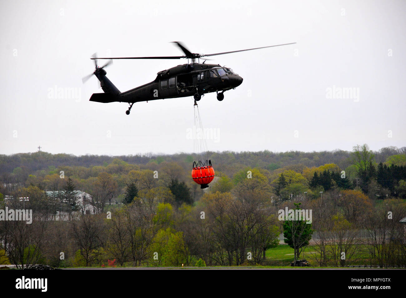 Soldati con Alfa Company, 2-104th supporto generale del battaglione di aviazione, 28 Combattere la Brigata Aerea condotta secchio di acqua della formazione in un UH-60 Black Hawk elicottero a Fort Indiantown Gap, Aprile 22, 2017. 28 soldati della cabina sono abili in questa manovra che viene eseguita per estinguere gli incendi. Foto Stock