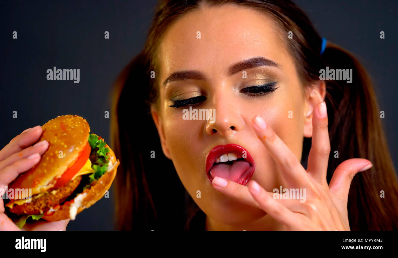 Donna di mangiare hamburger. La ragazza vuole mangiare fast food. Foto Stock