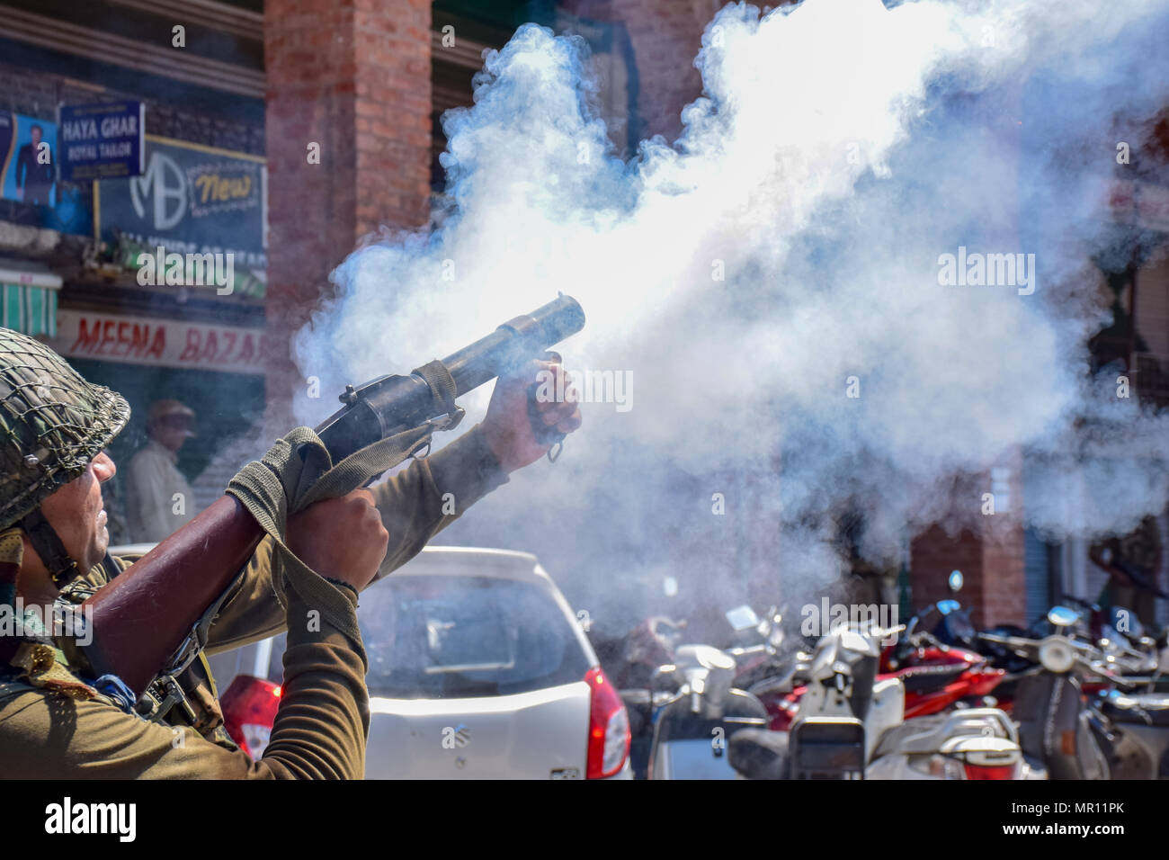 Il personale di polizia incendi di pneumatici shell fumo verso i manifestanti durante gli scontri nella città vecchia di Srinagar capitale estiva del Kashmir indiano dopo la preghiera del venerdì. Scontri scoppiati subito dopo la preghiera del venerdì in area del centro cittadino di Srinagar, Kashmir indiano, il venerdì. Diverse persone sono rimaste ferite dopo che le forze governative hanno sparato pistole di pellet e gas lacrimogeni gusci su persone che si sono riuniti dopo venerdì pomeriggio le preghiere che protestavano contro la regola di indiana nella regione contesa. Foto Stock
