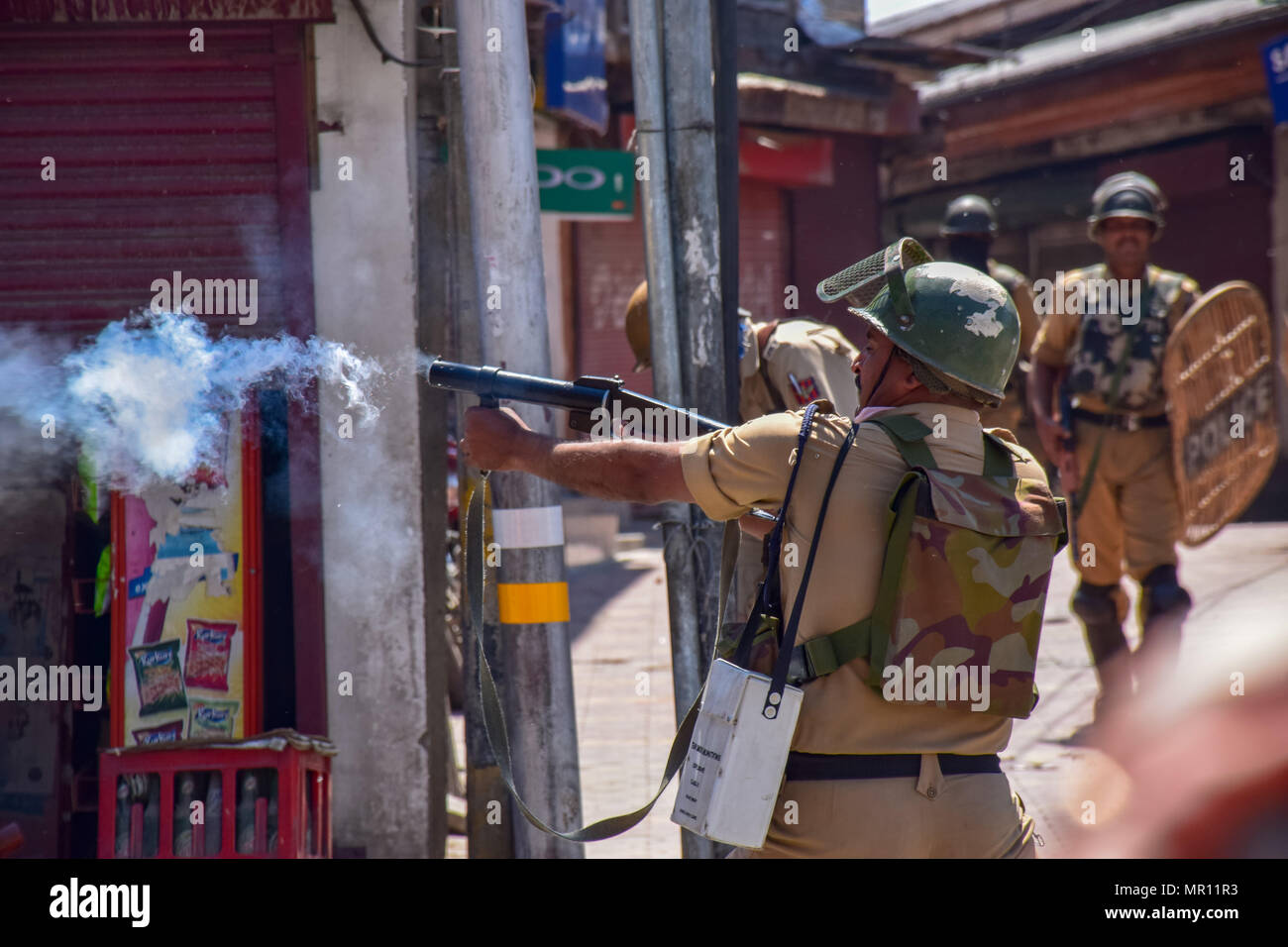 Il personale di polizia incendi di pneumatici shell fumo verso i manifestanti durante gli scontri nella città vecchia di Srinagar capitale estiva del Kashmir indiano dopo la preghiera del venerdì. Scontri scoppiati subito dopo la preghiera del venerdì in area del centro cittadino di Srinagar, Kashmir indiano, il venerdì. Diverse persone sono rimaste ferite dopo che le forze governative hanno sparato pistole di pellet e gas lacrimogeni gusci su persone che si sono riuniti dopo venerdì pomeriggio le preghiere che protestavano contro la regola di indiana nella regione contesa. Foto Stock