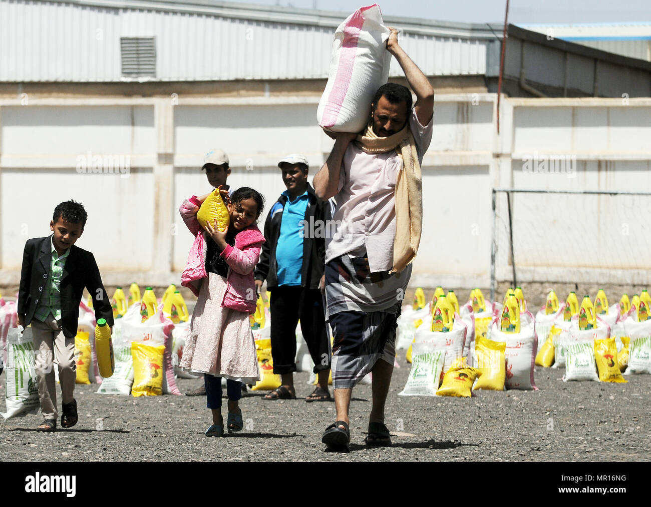 Sanaa, Yemen. 25 Maggio, 2018. Un yemenita dipendente statale e i suoi bambini portano le razioni di cibo in Sanaa, Yemen, il 25 maggio 2018. Yemen, che è stato in guerra dal 2015, rimane il mondo la peggiore crisi umanitaria. Tre quarti della popolazione, ovvero più di 22 milioni di persone, urgente bisogno di una qualche forma di aiuto umanitario, inclusi 8,4 milioni di persone che lottano per trovare il loro prossimo pasto. Credito: Mohammed Mohammed/Xinhua/Alamy Live News Foto Stock