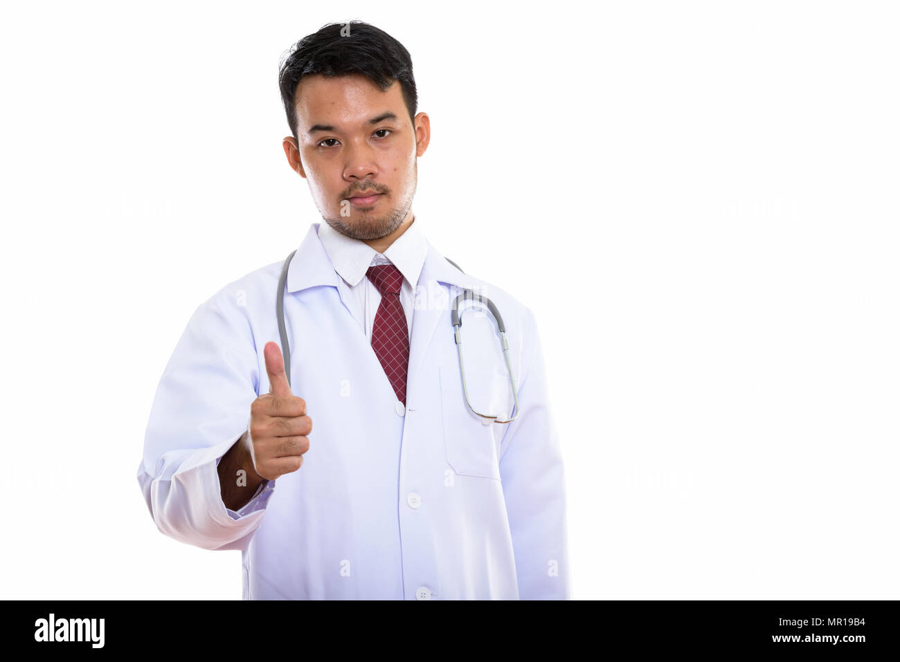 Studio shot del giovane uomo asiatico medico dando pollice in alto Foto Stock