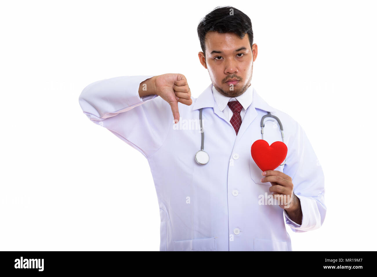 Studio shot del giovane uomo asiatico medico tenendo cuore rosso e givi Foto Stock