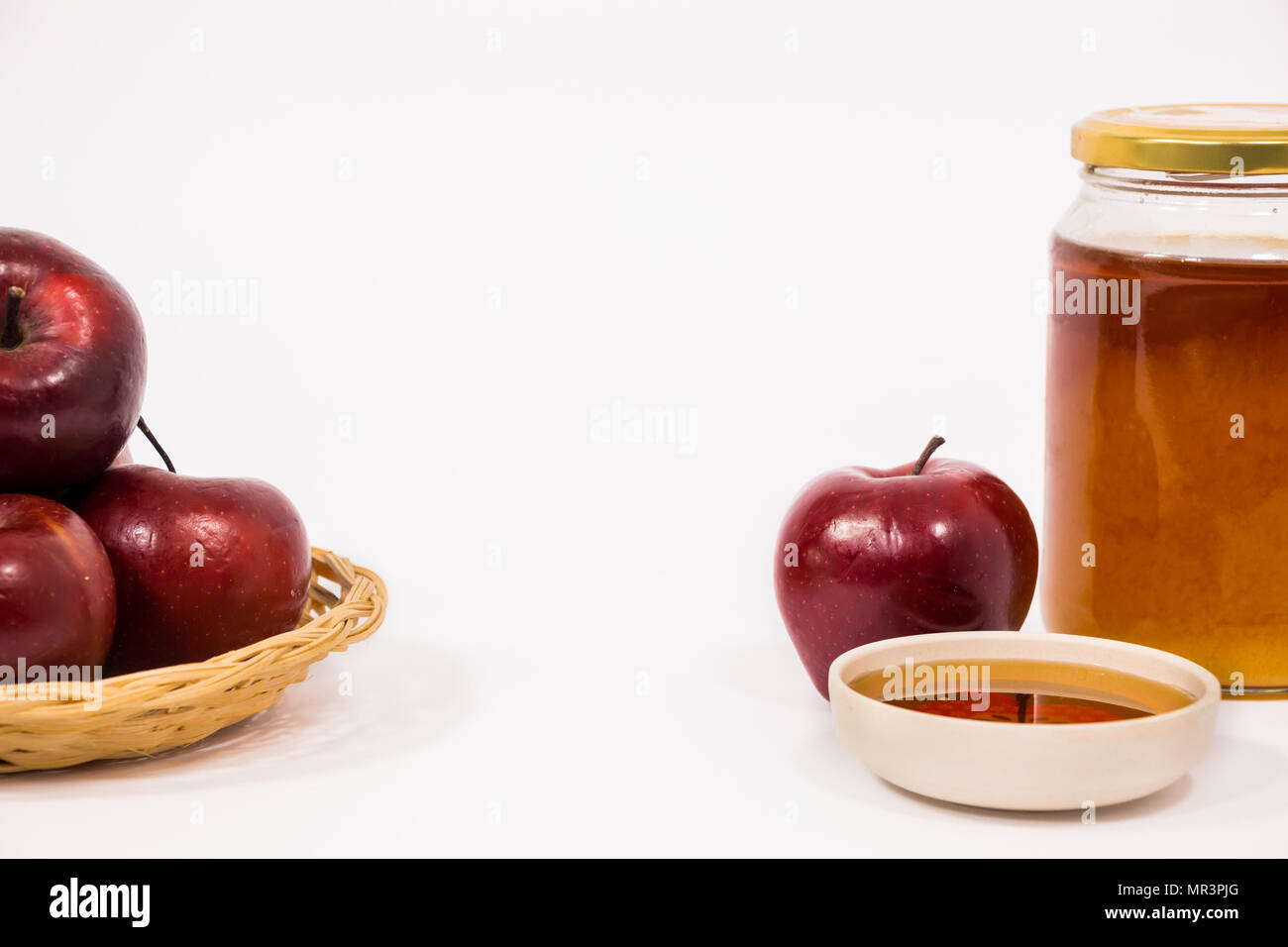 Pila di mele e red apple e un vasetto di miele ciotola di miele isolato su uno sfondo bianco. Simboli ebraica di nuovo anno - Rosh Hashanah. Foto Stock