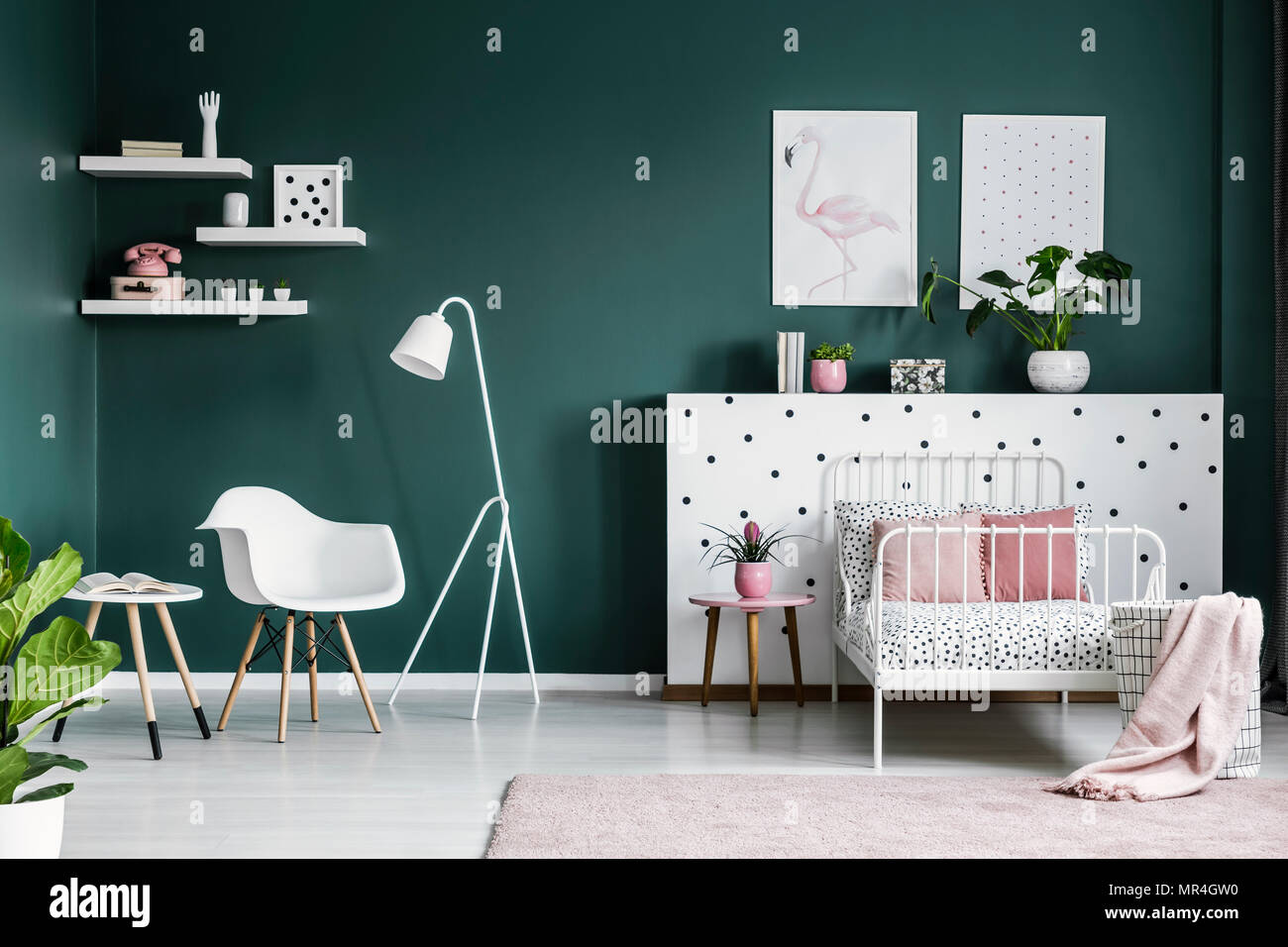 Rosa pastello decorazioni in un scandi interiore camera da letto per una ragazza adolescente con moderni e arredi bianchi e muri verde scuro Foto Stock