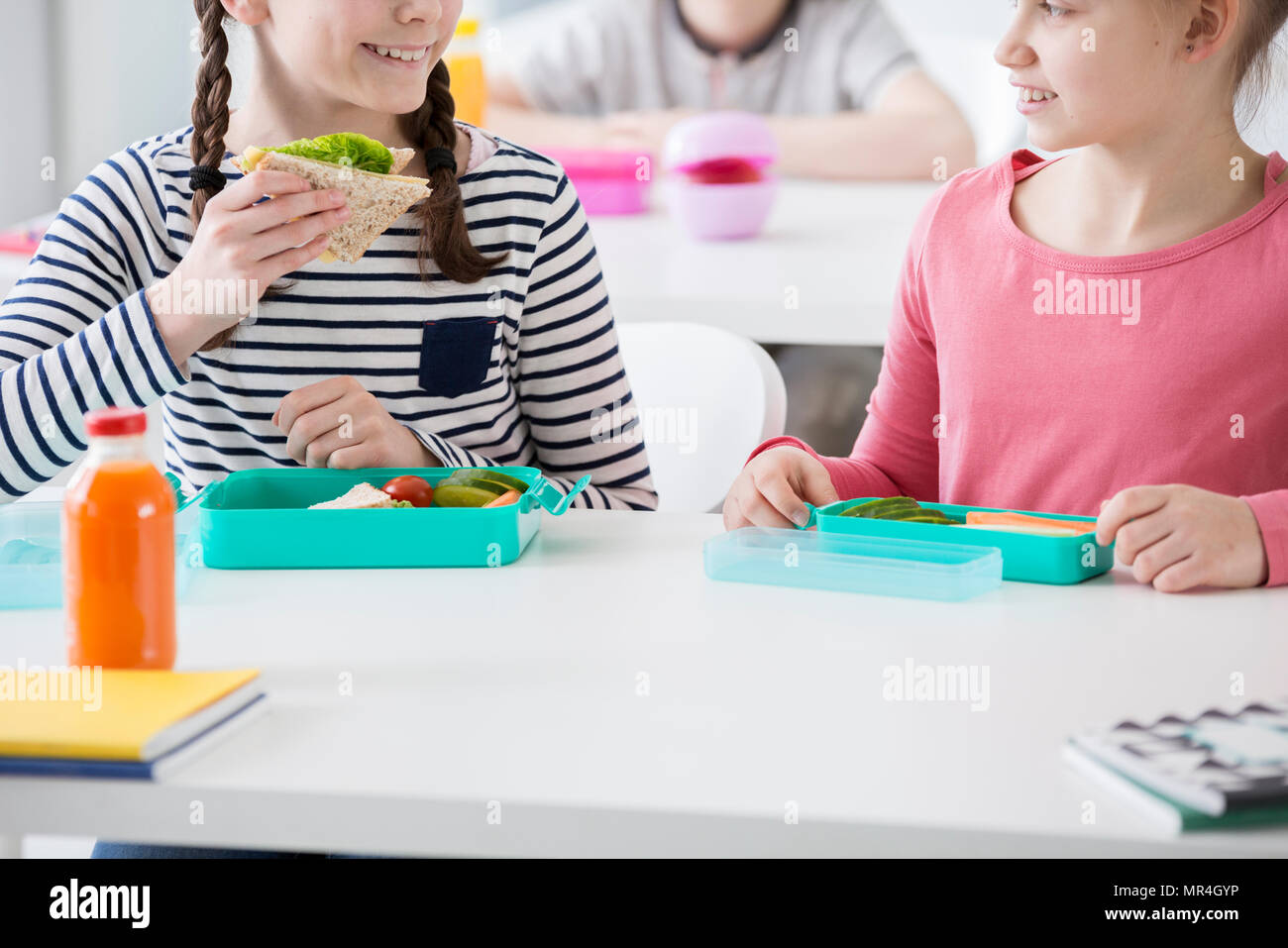 Close-up della ragazza sorridente mangiare toast eco durante la pausa colazione a scuola Foto Stock