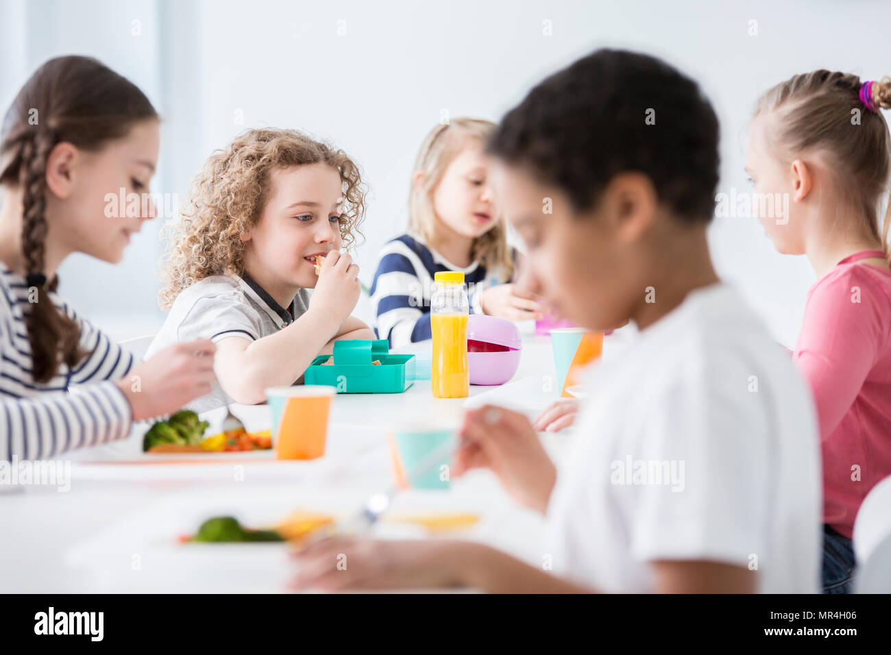 Gruppo di bambini di mangiare le verdure nella sala da pranzo della scuola Foto Stock