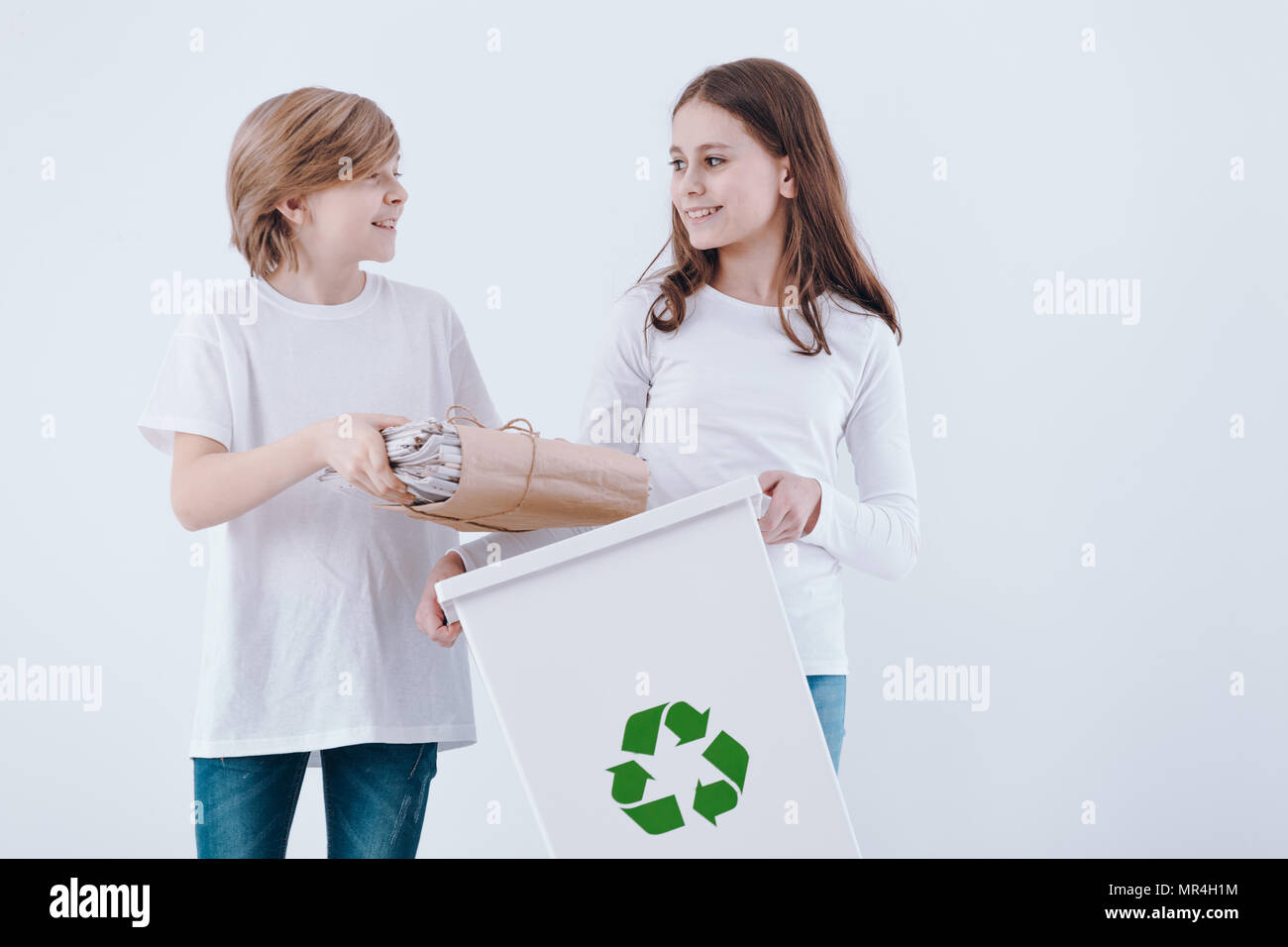 I bambini la segregazione di rifiuti, in piedi contro lo sfondo bianco Foto Stock