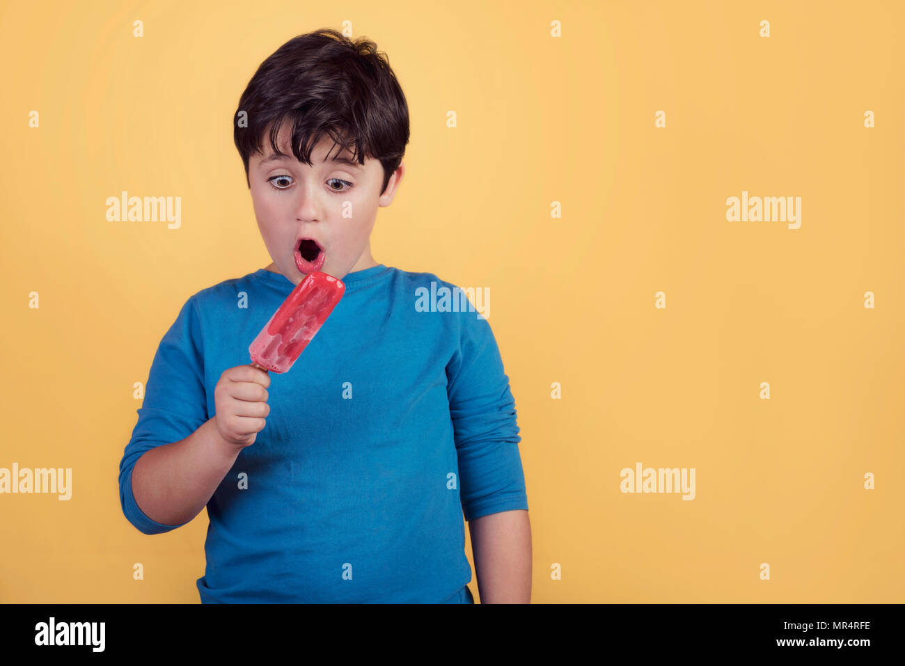 Ragazzo con un gelato alla fragola su sfondo giallo Foto Stock
