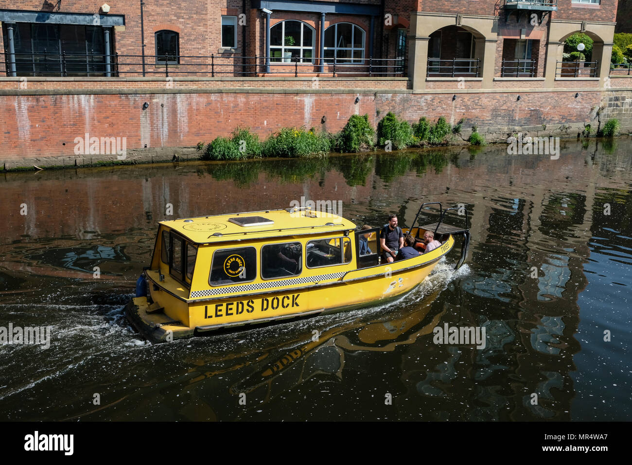 Con un taxi acqueo passando il molo ristrutturato dal fiume Aire in zona lungomare, Leeds, West Yorkshire, Inghilterra, Regno Unito. Foto Stock